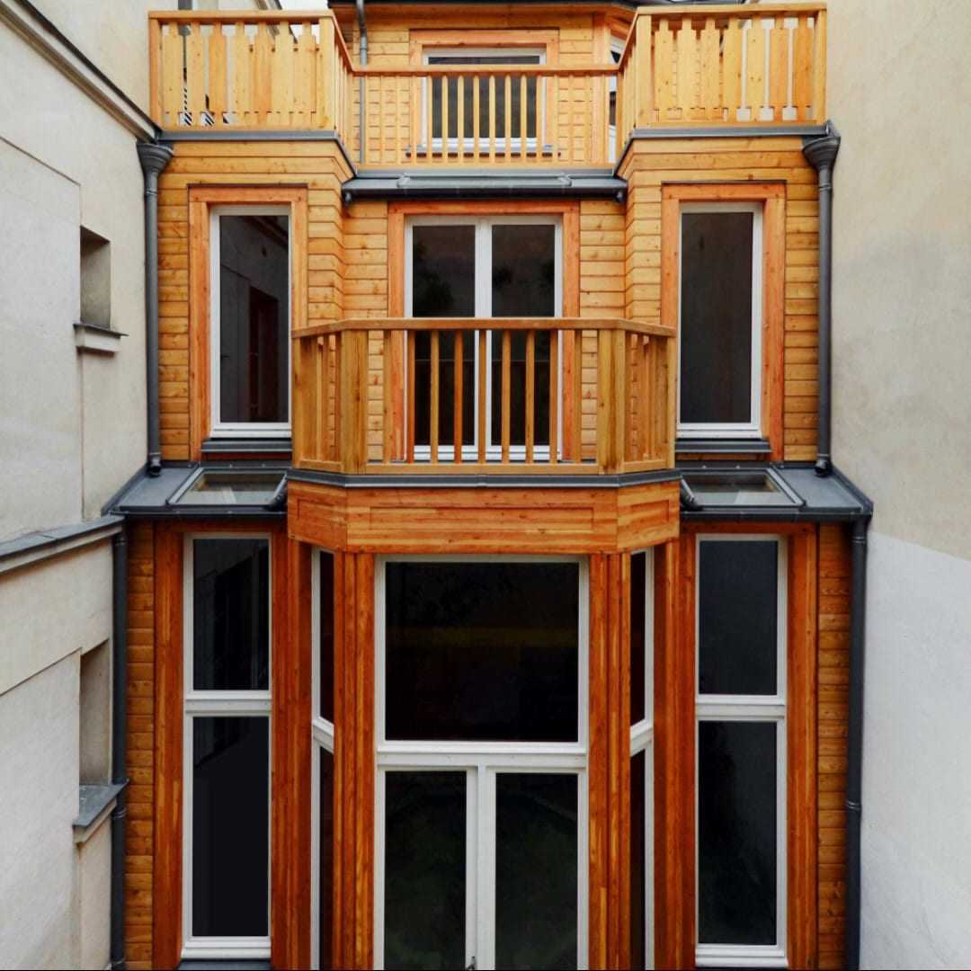 Façade en bois d’une maison à ossature bois de trois niveaux, entre deux immeubles parisiens.